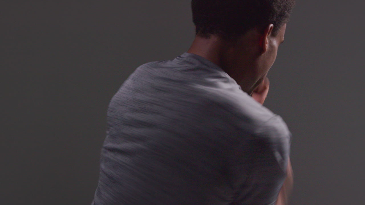 남성 권투 선수가 체육관에서 훈련하고 검은 바탕에 맞서 싸우기 위해 준비하는 뒷면 스튜디오