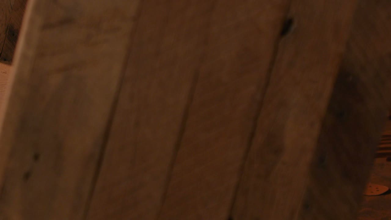 la cámara gira hacia la izquierda para revelar a un carpintero clavando un clavo en una estantería