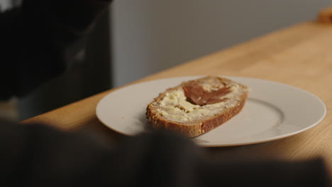 smearing chocolate cream onto a bread with butter