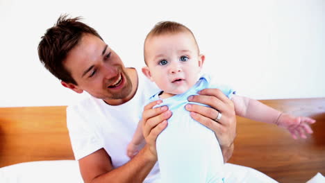 padre feliz jugando con su bebé en la cama
