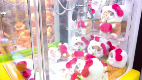 Claw machine filled with plush cat toys and Garfield dolls in a bright arcade