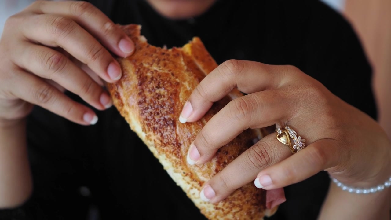 Woman Holding and Eating a Fresh Toasted Sandwich