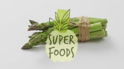 animación de texto de super alimentos sobre un paquete de espárragos atado con hilo