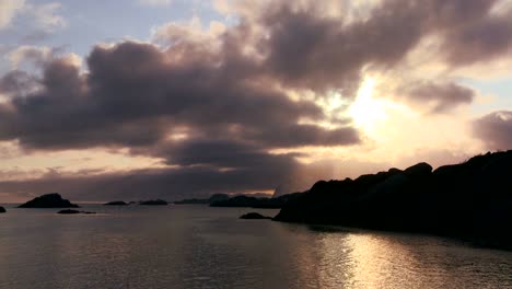 Lapso-De-Tiempo-De-Nubes-Doradas-Al-Atardecer-Detrás-De-Una-Costa-En-Medio-De-Los-Fiordos-Al-Norte-Del-Círculo-Polar-ártico-En-Las-Islas-Lofoten,-Noruega