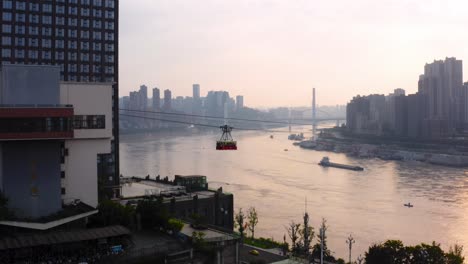 yangtze river cableway car crosses in front of chongqing city china at golden hour sunset, aerial tracking