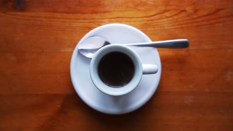 down shot of a hot espresso cup with plate and spoon