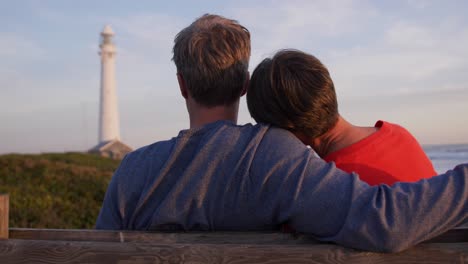 couple embracing by the sea near a lighthouse