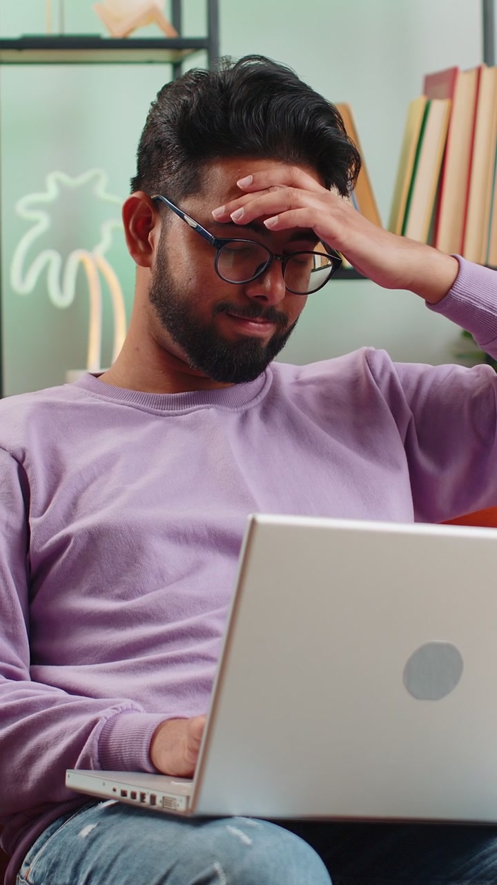 Stressed indian man looking at unpaid bank debt loan doing paperwork planning budget throws bills