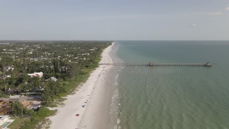 fishing pier on tropical sea coast juts out from shallow sandy beach