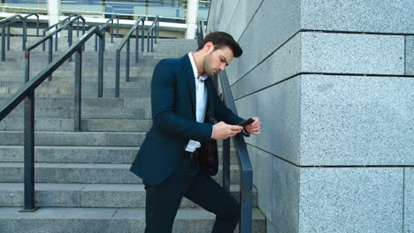 side view businessman standing with phone at street. man smiling with phone