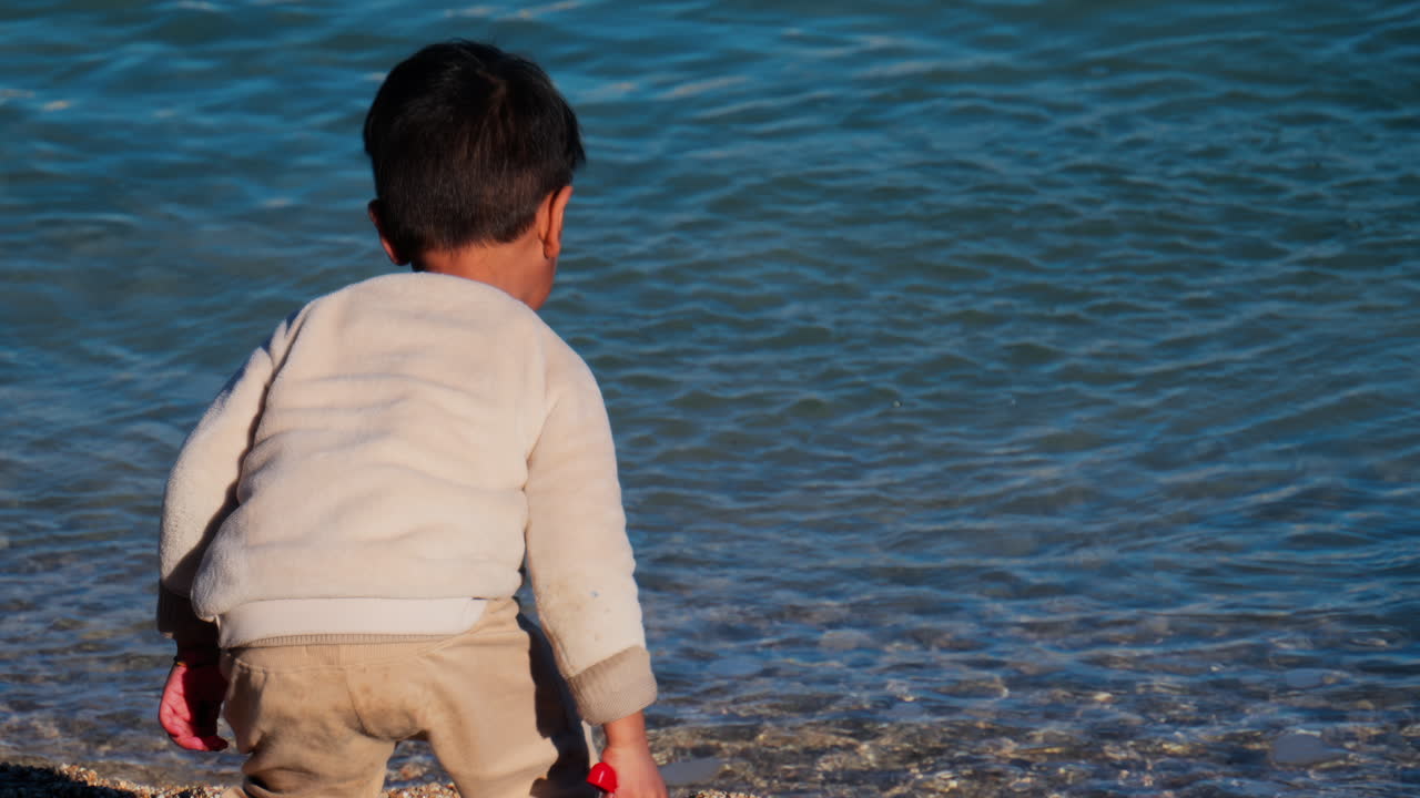 Little boy throwing sand in the sea on the beach