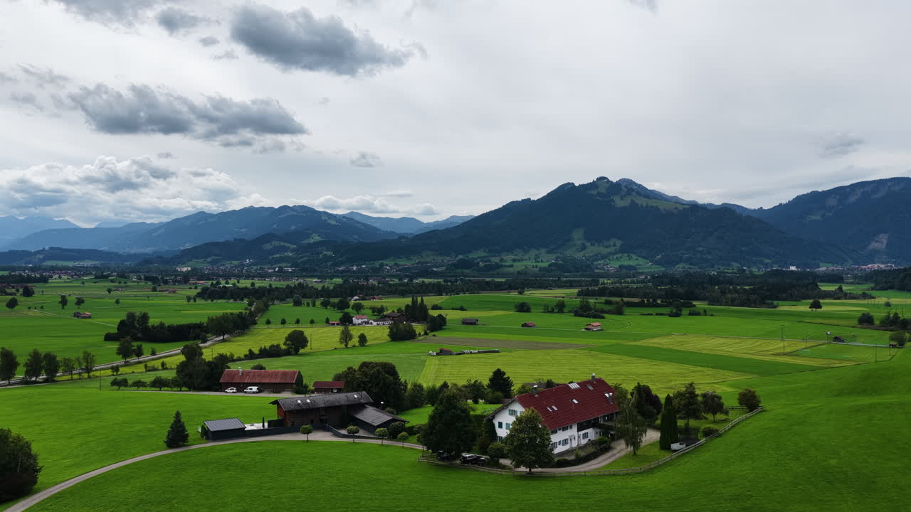 Vista aerea con drone di terreni agricoli rurali e campi verdi in un'ampia valle alpina circondata da montagne nelle Alpi austriache. Paesaggio rurale scenografico con fattorie tradizionali e natura.