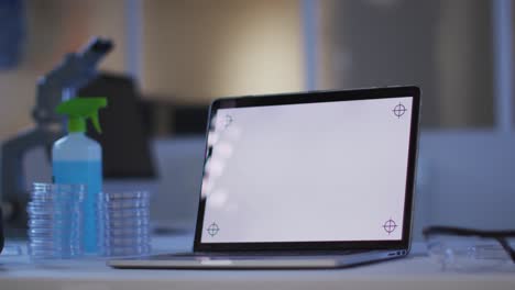 Laptop-with-illuminated-screen-at-a-workstation-in-an-empty-laboratory