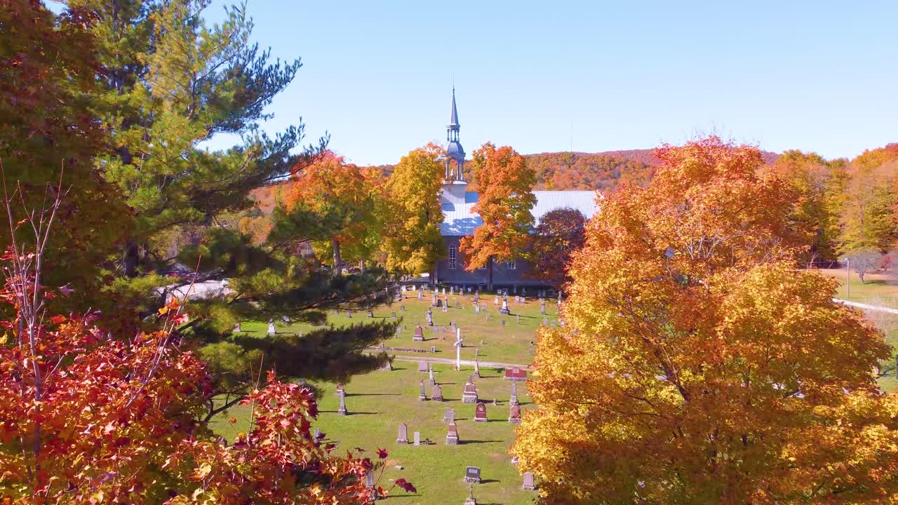 A gentle drone flight glides through fall foliage, opening to a graveyard and church.