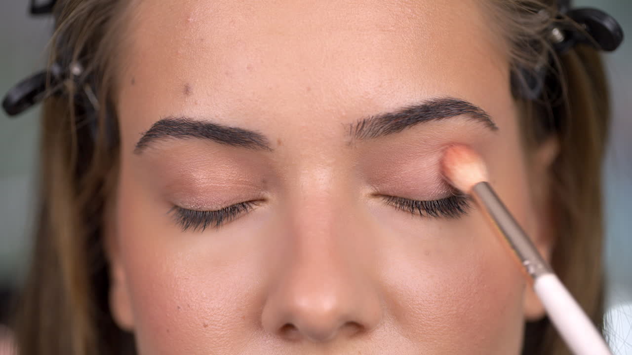 Close-up of a person applying eyeshadow with a makeup brush