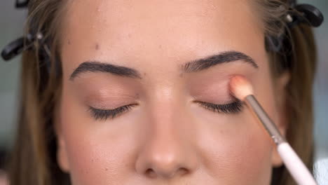 close-up of a person applying eyeshadow with a makeup brush