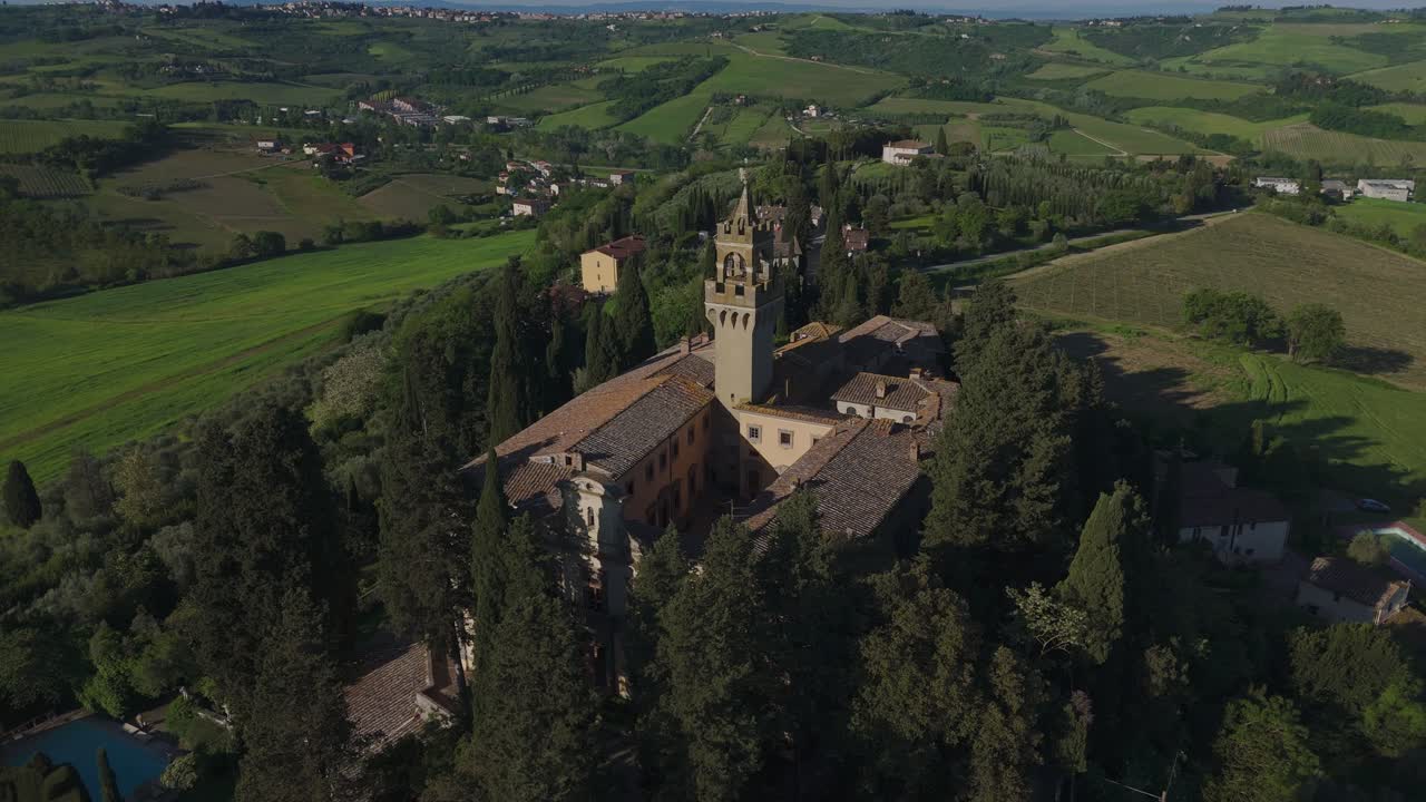 Daylight aerial orbit of Castello di Montegufoni in Tuscany, surrounded by green hills and cypress trees. This historic castle near Florence is captured in stunning clarity and vibrant natural light.