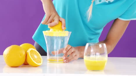 woman preparing sweet lime juice from juicer against violet background