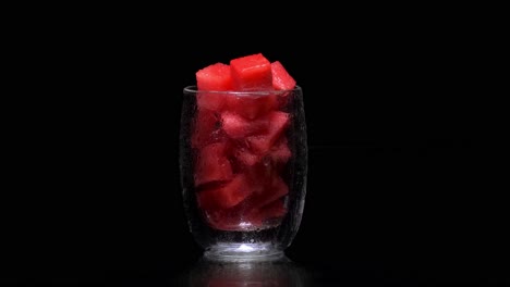 glass filled with watermelon cubes, water dripping from it