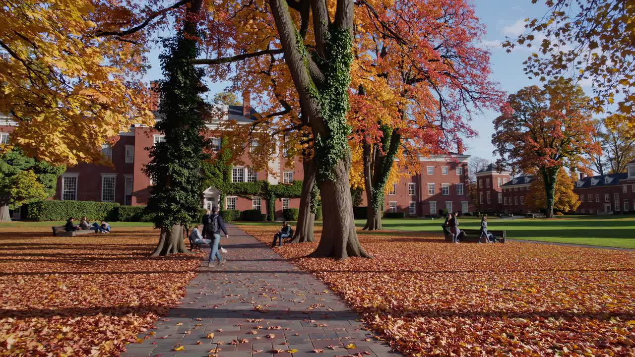 Wide-angle video captures a serene college campus in autumn, with vibrant foliage and students