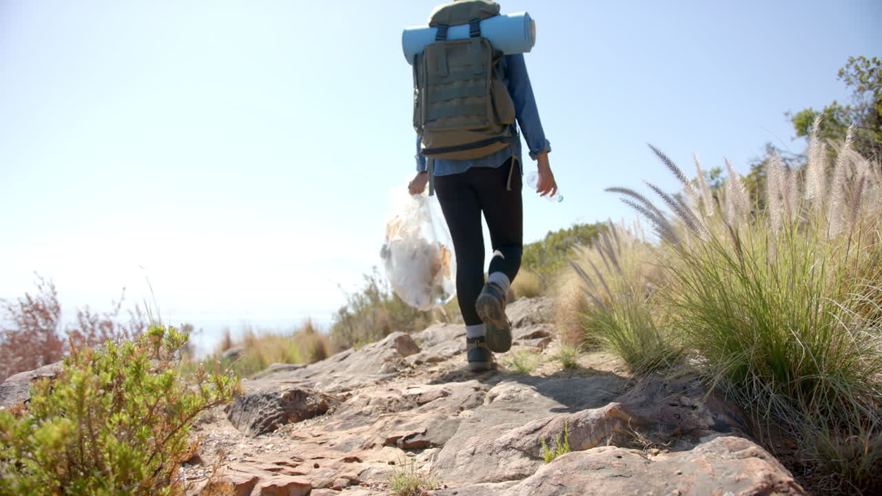 Hiking on rocky trail, person carrying backpack and collecting trash