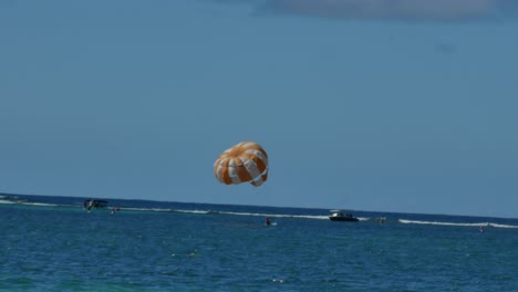 a man touching the water and going up again while practices parasailing