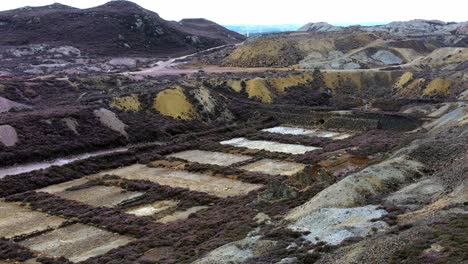 Parys-mountain-abandoned-historic-copper-mine-red-stone-mining-industry-landscape-aerial-view-tilt-up