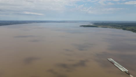 Aerial-view-of-a-transport-boat-navigating-the-vast-Paraná-River,-connecting-Argentina-and-Paraguay,-showcasing-the-importance-of-river-transportation-for-trade-and-commerce