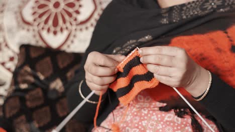 mujer india tradicional teje con agujas artesanales y lana negra y roja