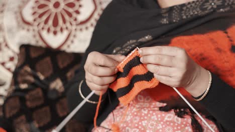 traditional indian woman knits with craft needles and black and red wool