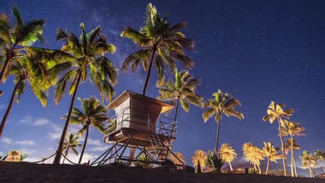 night timelaspe of haleiwa beach as clouds and stars pass behind a lifeguard station - oahu hawaii