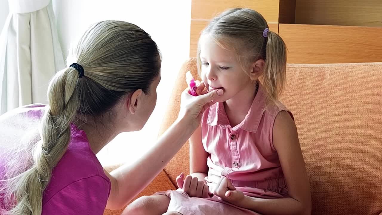 mãe a aplicar maquiagem à filha.