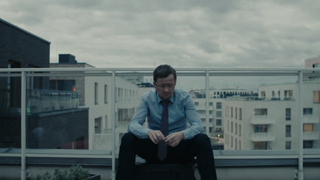 a sad man in a shirt smokes a cigarette on the balcony