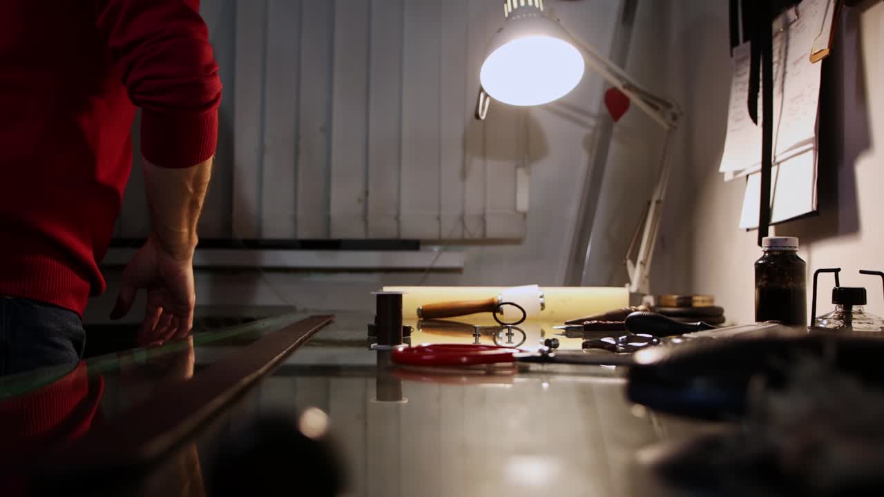 taller de cuero - un hombre calienta y pulida los bordes de un bucle de cinturón