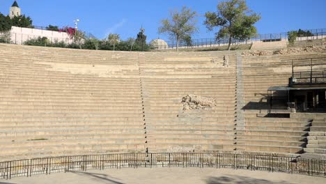 Empty-ancient-Roman-amphitheater-in-Carthage,-Tunisia,-with-clear-skies-and-surrounding-greenery