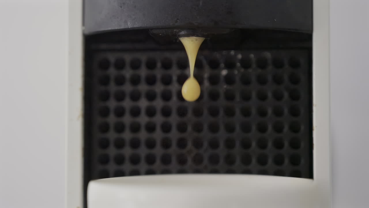 Primo piano di caffè che viene versato da una macchina in una tazza bianca