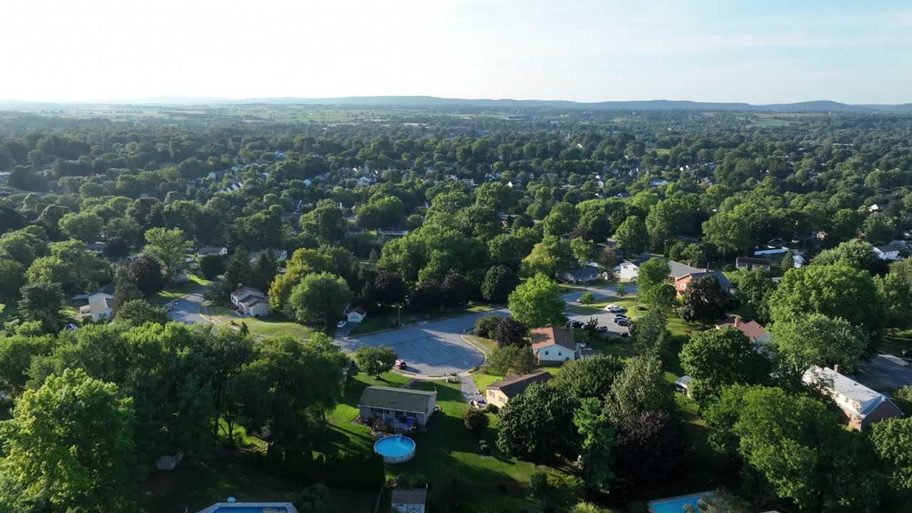 Aerial establishing shot of quiet and peaceful neighborhood in suburb ion america. Sunny day with green trees in summer. Houses and homes with garden on hill
