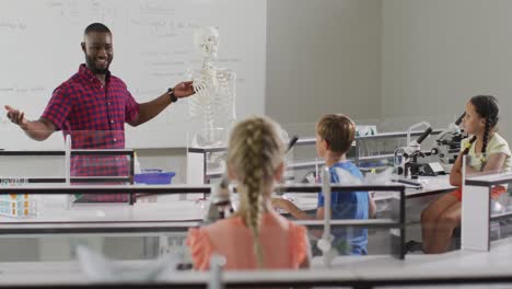 video de un feliz maestro afroamericano con una clase de alumnos diversos durante la lección de anatomía