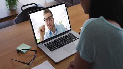mujer afroamericana haciendo una videollamada con un colega de oficina masculino en una computadora portátil en casa