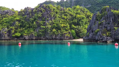 Turquoise-Tropical-Lagoon-on-Exotic-Island-Under-Steep-Limestone-Cliffs-and-Hills