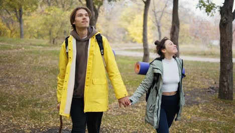 Couple-walking-in-the-forest-enjoying-fine-sunny-weather-with-backpacks