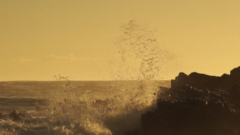 Rough-Sea-Waves-Crashing-On-Rocks-Creating-Huge-Spray-During-Golden-Sunset---Close-Up-Static-Shot