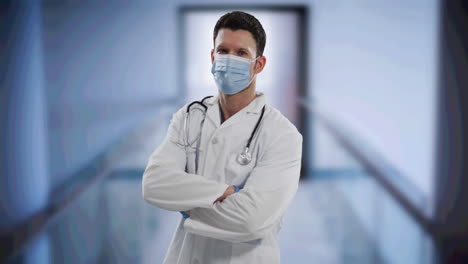 médico caucásico de sexo masculino con máscara de cara de pie con los brazos cruzados