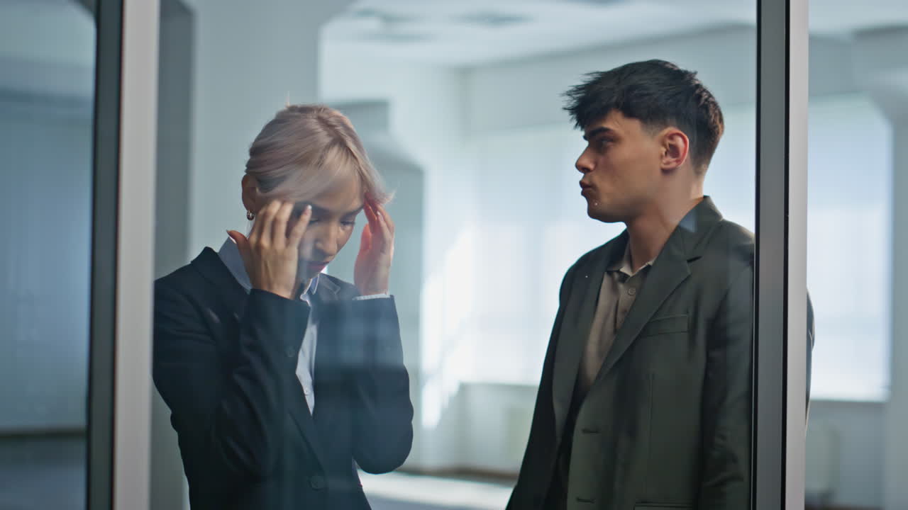 Two colleagues feeling worried at office hall closeup. Sad coworkers thinking