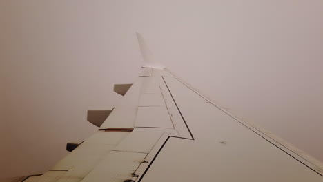 vista del punto de vista del pasajero del ala de un avión de transporte que sale de una gruesa capa de nubes