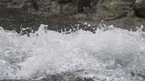 Slow-motion-close-up-of-rushing-water-at-Goa-Rang-Reng-waterfall-in-Bali,-Indonesia