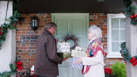 grandparents being greeted by family as they arrive for visit on christmas day with gifts