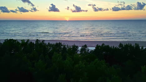 A-panoramic-view-of-the-sunset-over-the-Irbe-River,-with-the-dunes-silhouetted-in-the-foreground