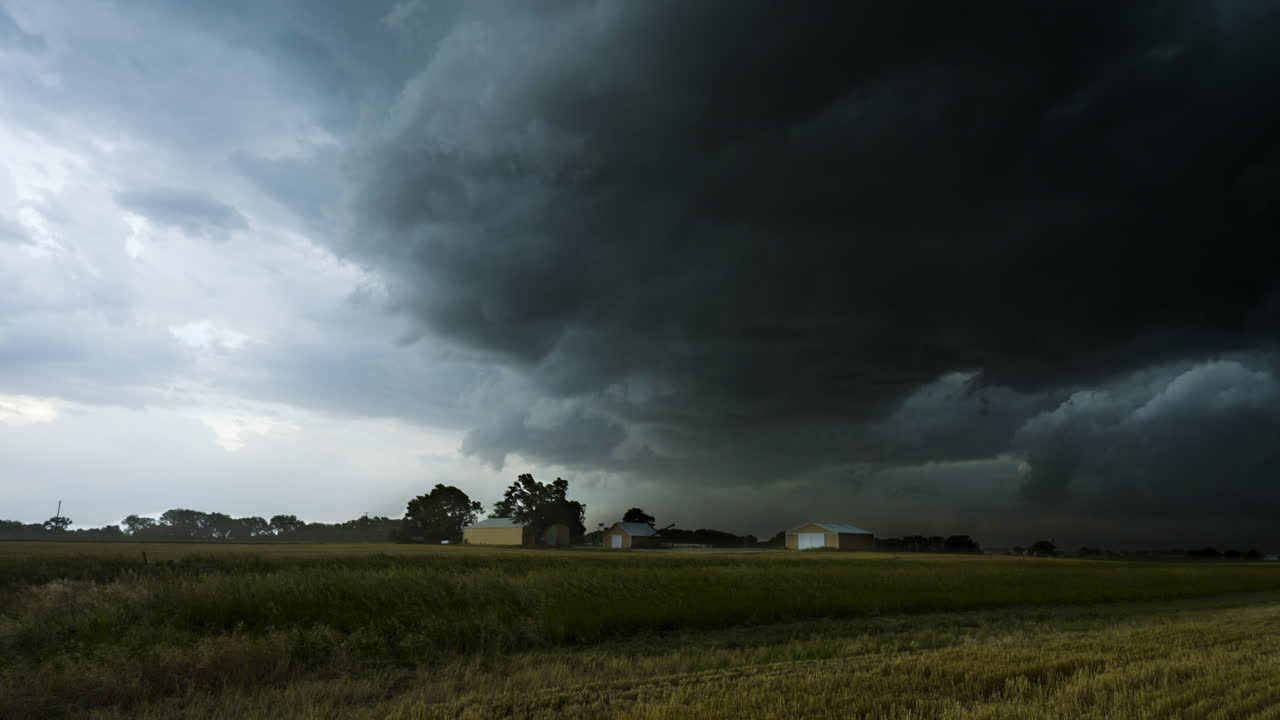 Strong storm winds blow across a farm as a dark storm moves in