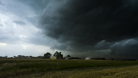 strong storm winds blow across a farm as a dark storm moves in